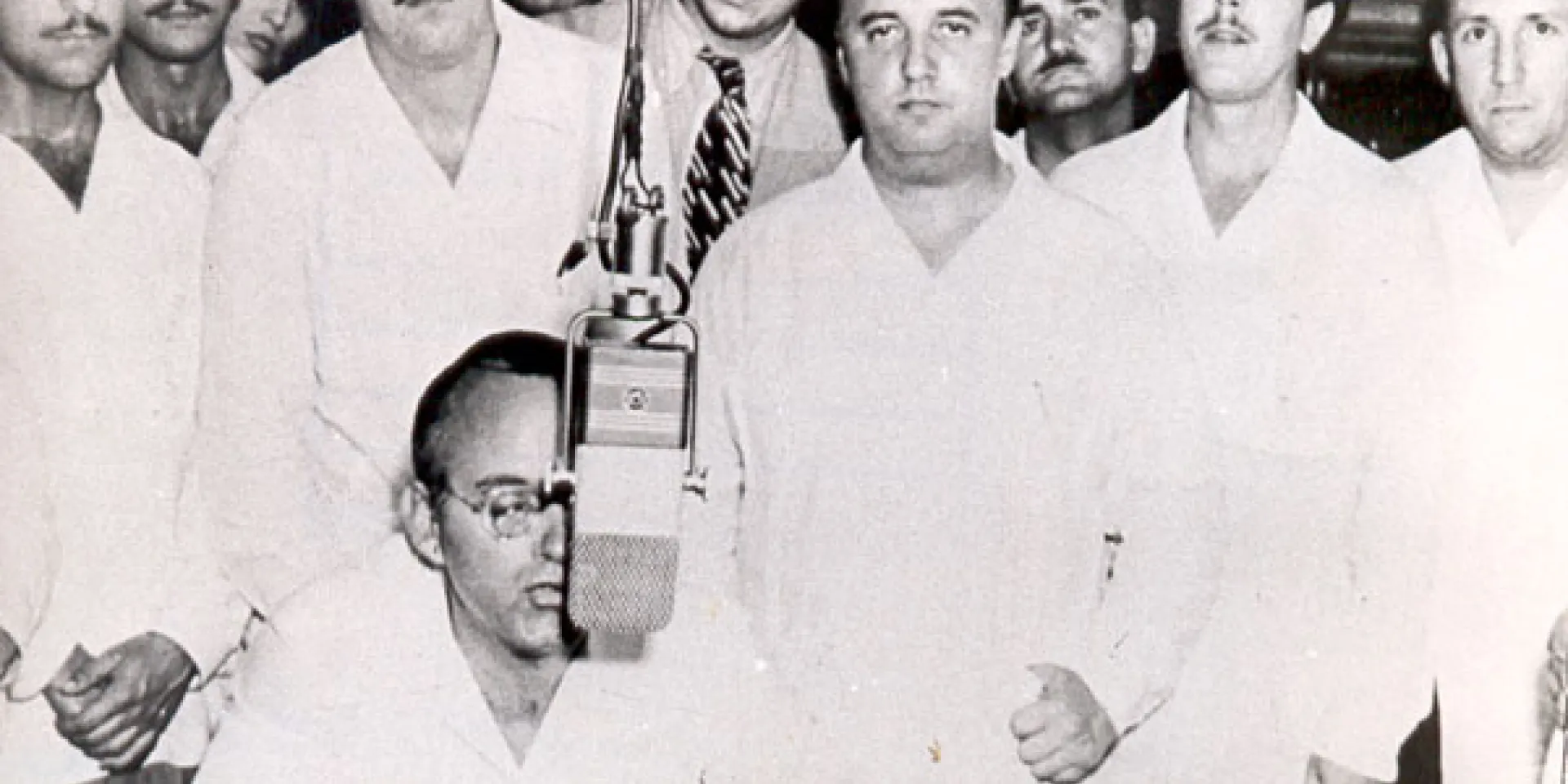 Eduardo Chibás en una de sus alocuciones radiales. De pie, en primera fila (tercero de derecha a izquierda), Roberto Agramonte. Detrás de este, el joven abogado Fidel Castro. (Foto: Autor no identificado)